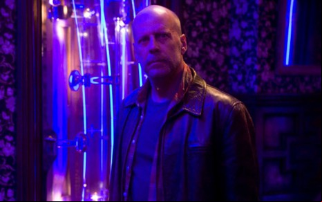 Em um ambiente com luz azulada, Bruce Willis está olhando para frente em cena do filme Substitutos (2009)