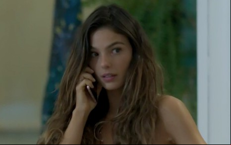 Isis Valverde em cena de A Força do Querer: personagem segura um celular com a mão direita e olha desconfiada para o seu redor