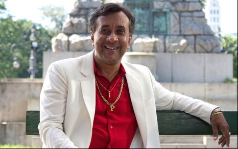 O sorridente Paulinho Gogó (Maurício Manfrini) em um banco de praça em cena de No Gogó do Paulinho