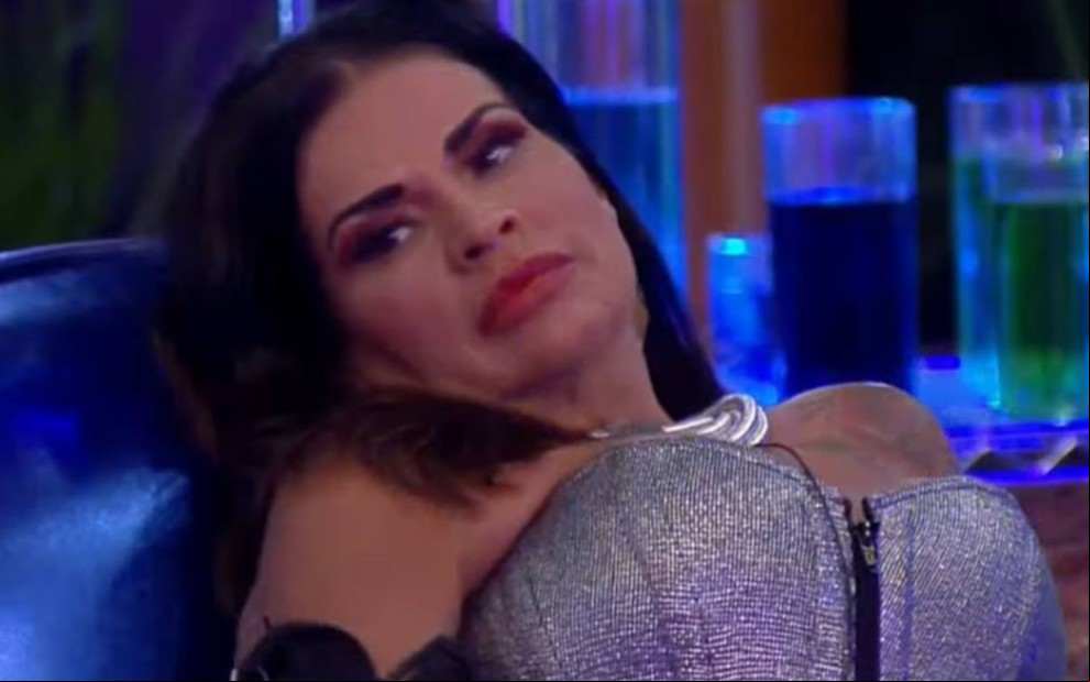 Solange veste cinta prata e está deitada em um sofá