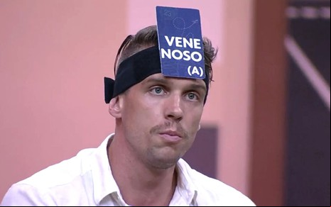 Cristian Vanelli com uma placa de venenosa colada na cabeça no Jogo da Discórdia do BBB 23, da Globo