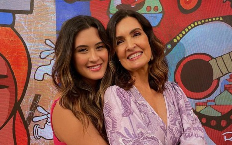 Fátima Bernardes de rosto colado com a filha Beatriz Bonemer; ambas vestem roupas coloridas