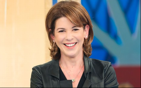 Daniela Beyruti durante gravação do especial dos 60 anos do Programa Silvio Santos; sorridente, ela veste jaqueta de couro preta