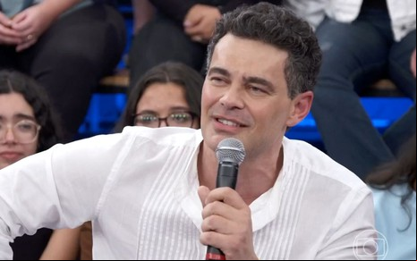 De camisa branca, Carmo Dalla Vecchia faz cara de apaixonado no cenário do Altas Horas