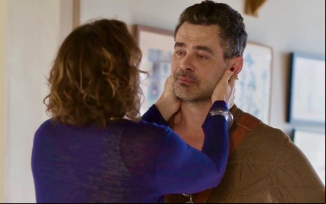 Paula Braun usa blusa azul e está de costas na imagem contracenando com Carmo Dalla Vecchia na novela Cara e Coragem