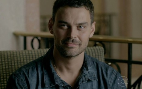 O ator Carmo Dalla Vecchia com um leve sorriso e expressão enigmática em cena de Império, novela da Globo