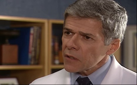 José Mayer caracterizada como César; ele usa um jaleco branco e tem os cabelos grisalhos. Ele dá um sorriso sacana em cena de Mulheres Apaixonadas