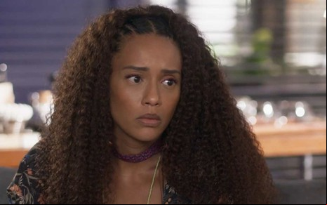 Atriz Taís Araujo olha para a frente com cara séria em cena de Cara e Coragem
