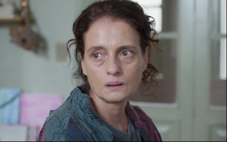 Denise Fraga em cena de Um Lugar ao Sol: atriz olha para alguém fora do quadro com expressão de tristeza