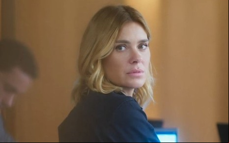 Em cena de Vai na Fé, Carolina Dieckmann está sentada, olhando para trás, com a expressão de desapontamento
