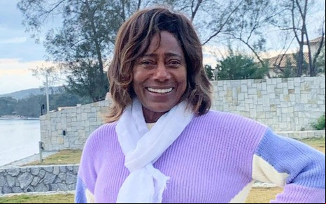 Gloria Maria usa uma blusa e posa sorridente em foto no Instagram