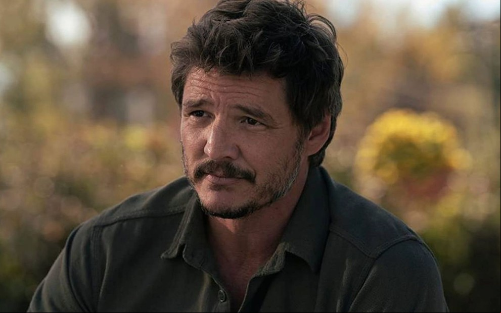 Joel (Pedro Pascal) veste camisa de botão na cor verde e sorri em cena de The Last of Us