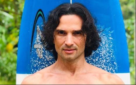 Jeff Machado posando em frente a uma prancha de surf