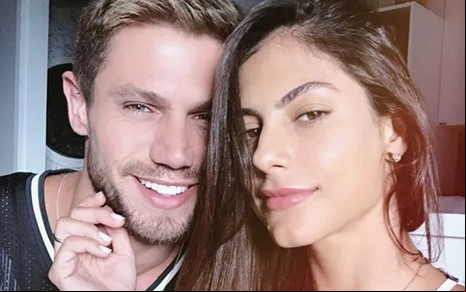 Jonas Sulzbach à esquerda tem o rosto acariciado por Mari Gonzalez em uma imagem que foca em seus rostos