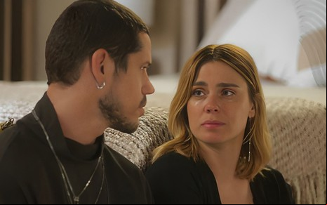 Lui (José Loreto) e Lumiar (Carolina Dieckmann) em cena de Vai na Fé, lado a lado, olhando sérios um para o outro