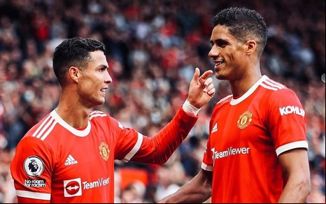 Raphael Varane e Cristiano Ronaldo com a camisa do Manchester United em um jogo de Champions e comemorando um gol