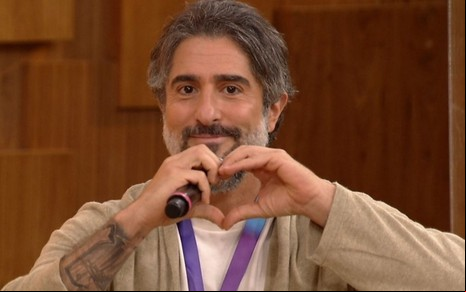 Marcos Mion faz sinal de coração com as mãos durante entrevista no programa Encontro