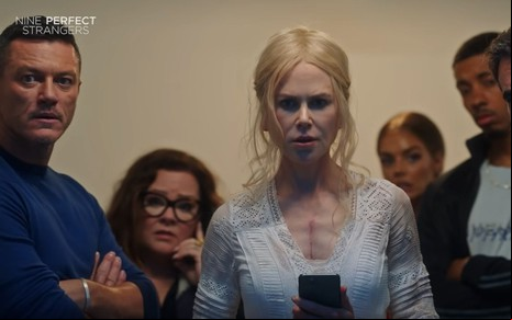 Na foto estão, da esquerda para a direita,  os atores Luke Evans, Melissa McCarthy, Nicole Kidman, Samara Weaving e Melvin Gregg. Todos enfileirados e olhando para frente com uma expressão de espanto.