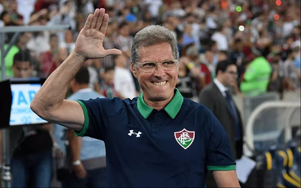 O técnico Oswaldo de Oliveira com camisa do Fluminense, mão direita aberta na altura da cabeça, em estádio