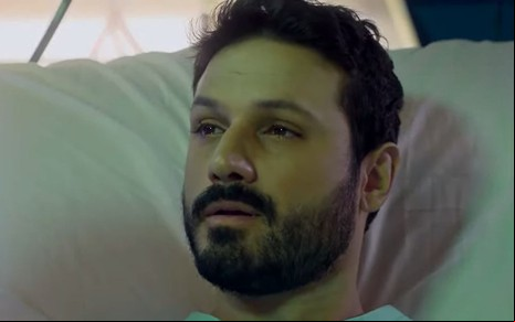 O ator Murilo Cezar como Marcelo em Poliana Moça; ele está deitado na cama olhando para frente com cara de frágil