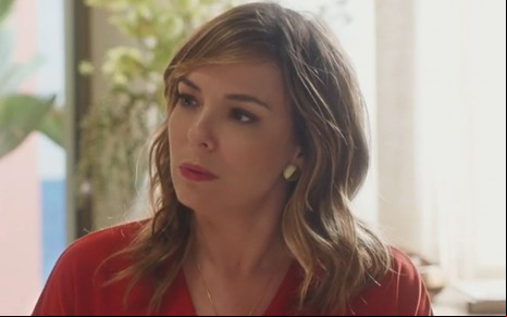 Clara (Regiane Alves) com expressão séria e blusa vermelha em cena de Vai na Fé