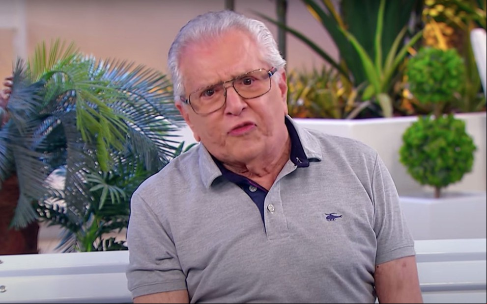 O apresentador e humorista Carlos Alberto de Nóbrega olha sério no banco do programa humorístico A Praça É Nossa, do SBT
