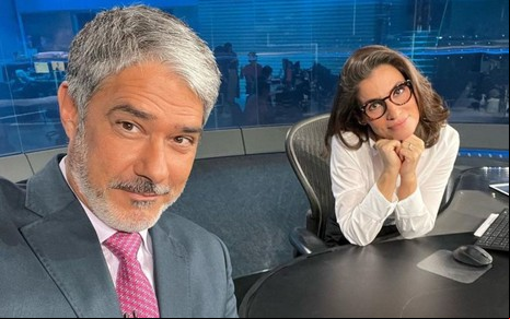 William Bonner e Renata Vasconcellos na bancada do Jornal Nacional, em pose nos bastidores