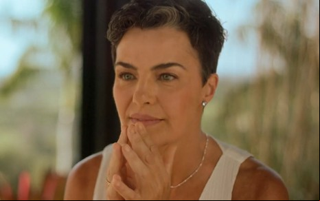 Ana Paula Arósio está com as mãos apoiadas no rosto, em uma publicidade de vitaminas