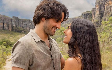 Os atores Tulio Starling e Larissa Bocchino frente a frente em cena de No Rancho Fundo, em cenário montanhoso
