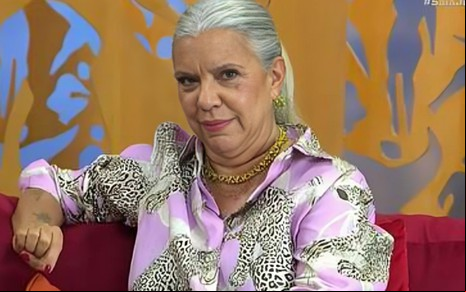 Astrid Fontenelle usa uma camisa rosa no sofá no Saia Justa