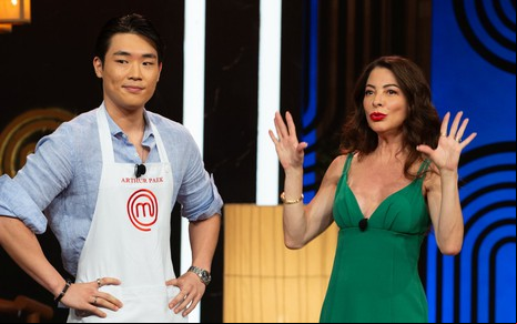 Arthur Paek sorri com a boca torta, enquanto Ana Paula Padrão ergue as mãos na frente de seu rosto, com os dedos abertos
