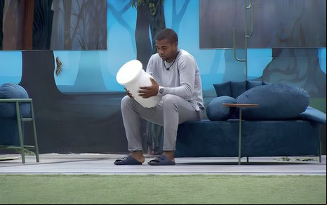 Davi Brito encara um vaso branco com forma de coruja na área externa do BBB 24