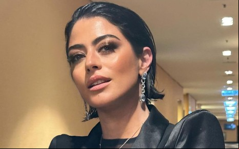 Carol Castro está com os cabelos curtos e oleosos e encara a câmera, séria