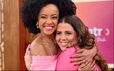 As apresentadoras Valéria Almeida e Tati Machado abraçadas no palco do Encontro