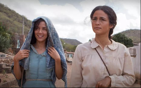 Marjorie Estiano cobre a cabeça com um lenço e Nanda Costa tem expressão séria em cena de Entre Irmãs