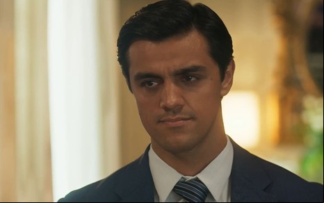 Felipe Simas caracterizado como Heitor; ele usa uma camisa social branca e está sério em cena de Fuzuê