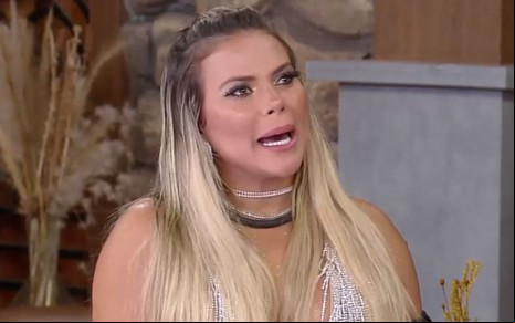 Kally Fonseca está com cabelos soltos e usa vestido prata durante a Cabine de Descompressão