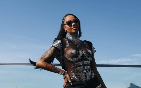 Ludmilla posa com um macacão preto em frente à vista do Aterro do Flamengo, no Rio