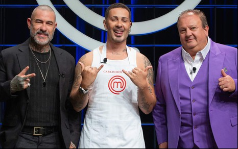 Henrique Fogaça, Carlinhos Maia e Erick Jacquin lado a lado, sorrindo para a câmera, no estúdio do MasterChef Brasil
