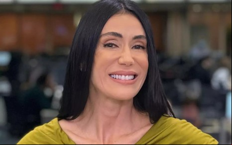 Michelle Barros está sorrindo, com as mãos na cintura