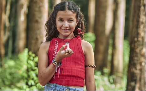 Marianna Santos segura um pingente de vagalume em foto promocional da série Luz, da Netflix