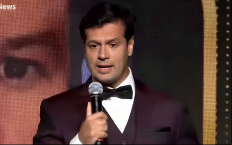 Thiago Feitosa discursa durante o Prêmio Comunique-se; ele veste terno e gravata