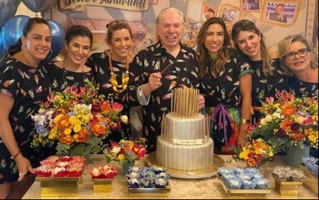 Silvio Santos com suas filhas em frente a mesa com bolo de aniversário. Da esquerda para a direita: Silvia, Rebeca, Daniela, Silvio, Patrícia, Renata e Cíntia