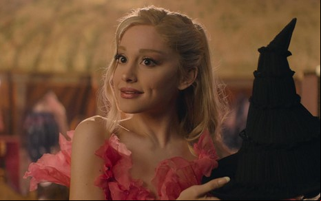 Ariana Grande segurando um chapéu de bruxa em cena de Wicked