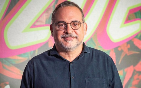 Fabricio Mamberti posando com sorriso discreto na estreia de Fuzuê, usando uma camisa preta e óculos