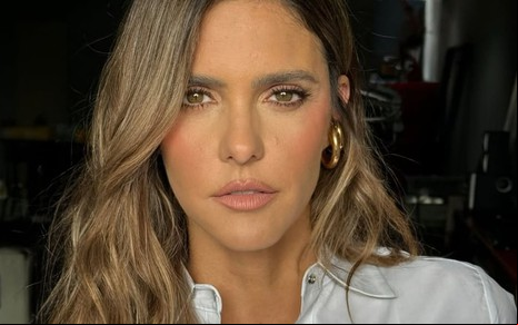 Fernanda Lima usa uma camisa branca e encara a câmera, séria