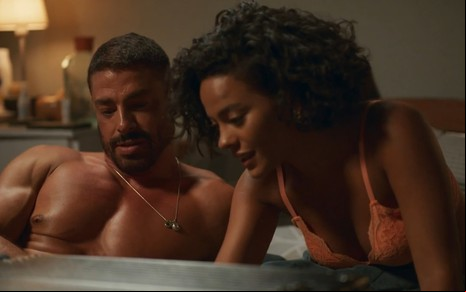 Cauã Reymond e Bella Campos estão juntos na cama, em roupas íntimas, em cena de Vale Tudo