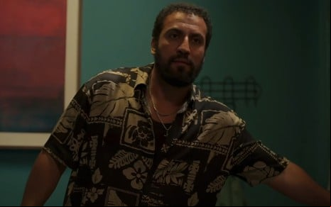 Com camisa estampada, Ricardo Teodoro inclina seu corpo para o lado enquanto tenta abrir porta