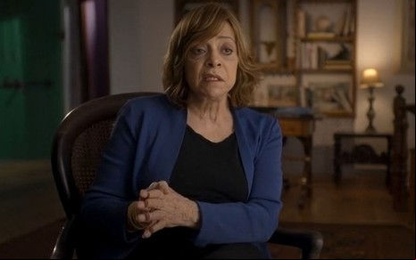Gloria Perez sentada e com expressão séria no documentário Pacto Brutal