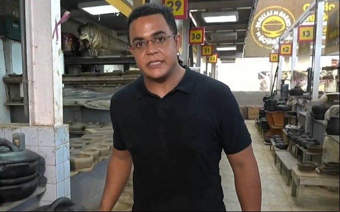 Marcelo Pereira usa uma camiseta preta e está num galpão cheio de as de barro